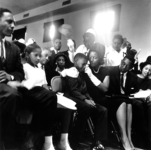 A group of people at the funeral of Medgar Evers. In the foreground, Myrlie Evers consoles her son, who is crying.
